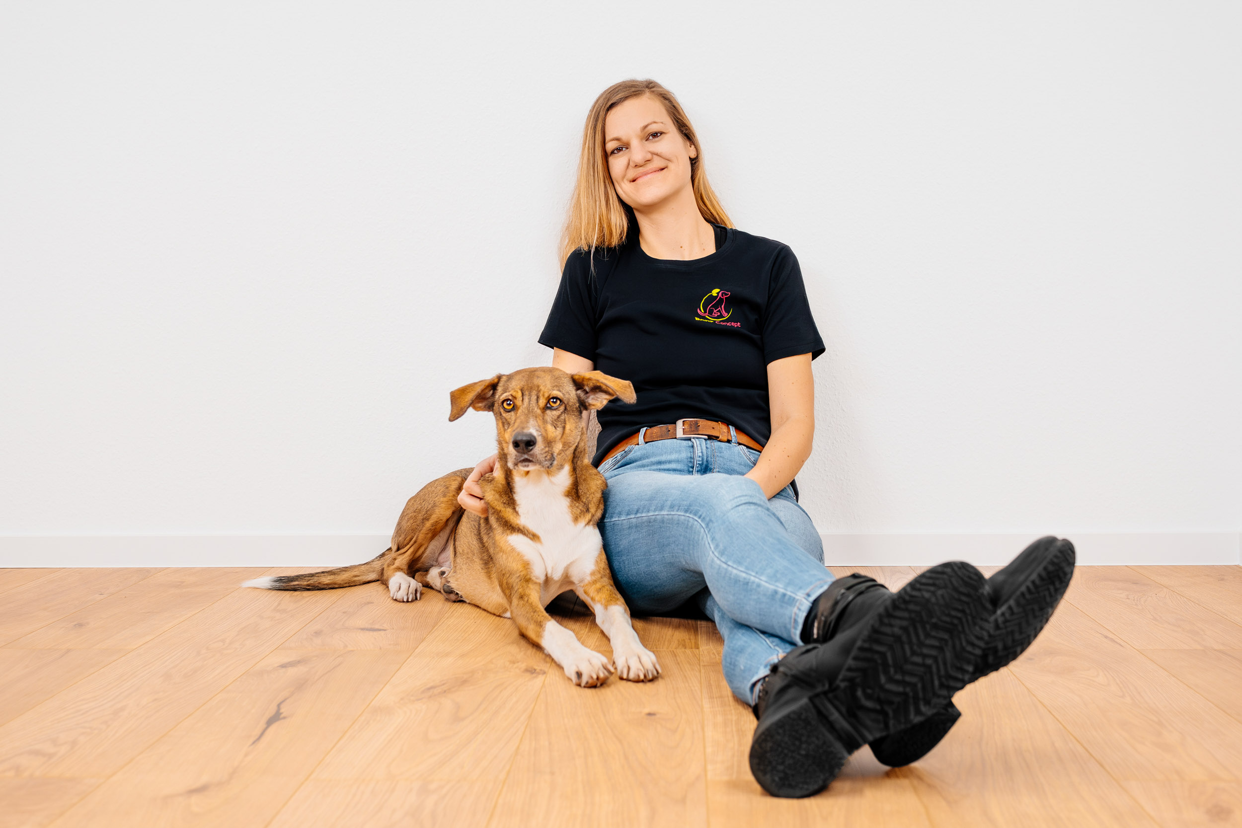 BARF-Concept Hundeernährungsberatung Teresa sitzt vor weißer Wand, kuschelt mit Hund